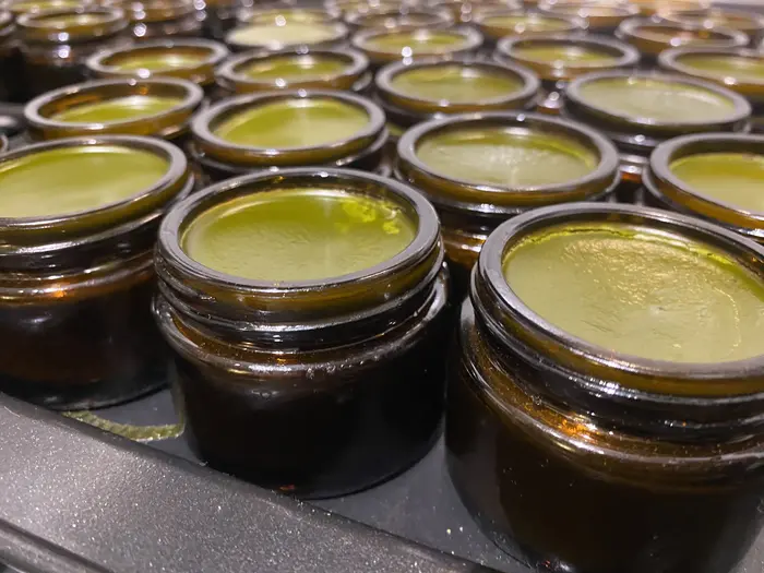A fresh batch of Essential Leaf comfrey and arnica balm in open amber glass jars